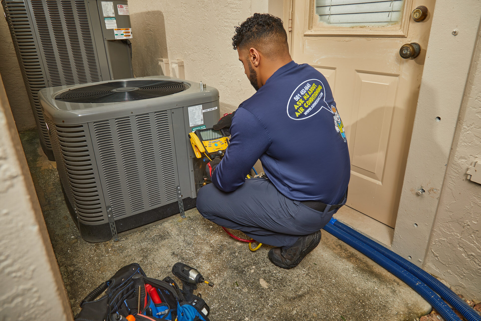 Air We Go technician diagnosing an AC condenser in Palm Beach County